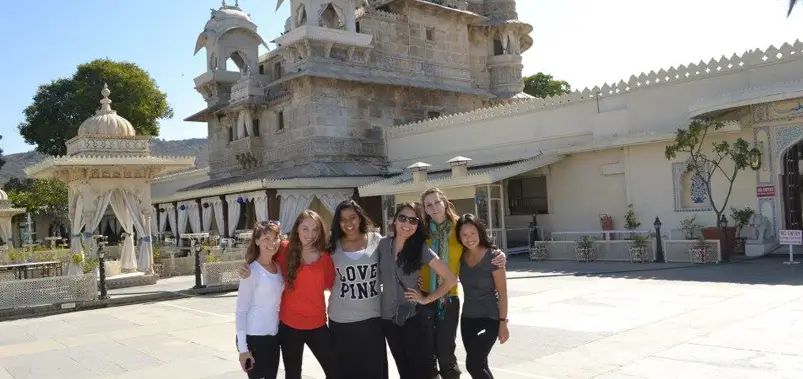 Group of friends posing for a photo in a historic courtyard with traditional Indian architecture