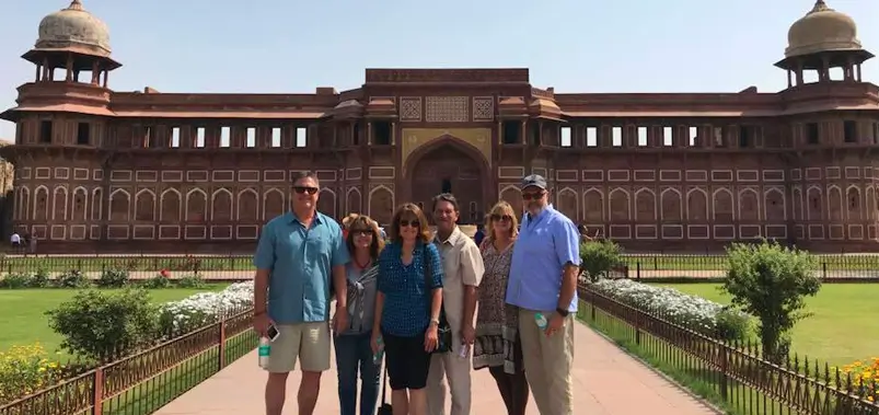 Group of tourists posing in front of a grand historic mosque with prominent domes and minarets